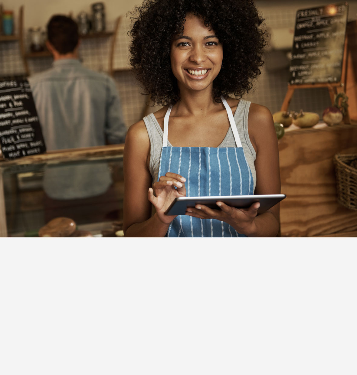 Image of a lady wearing an apron and holding a tablet in a cafe
