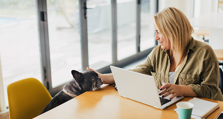 woman working from home with laptop and dog